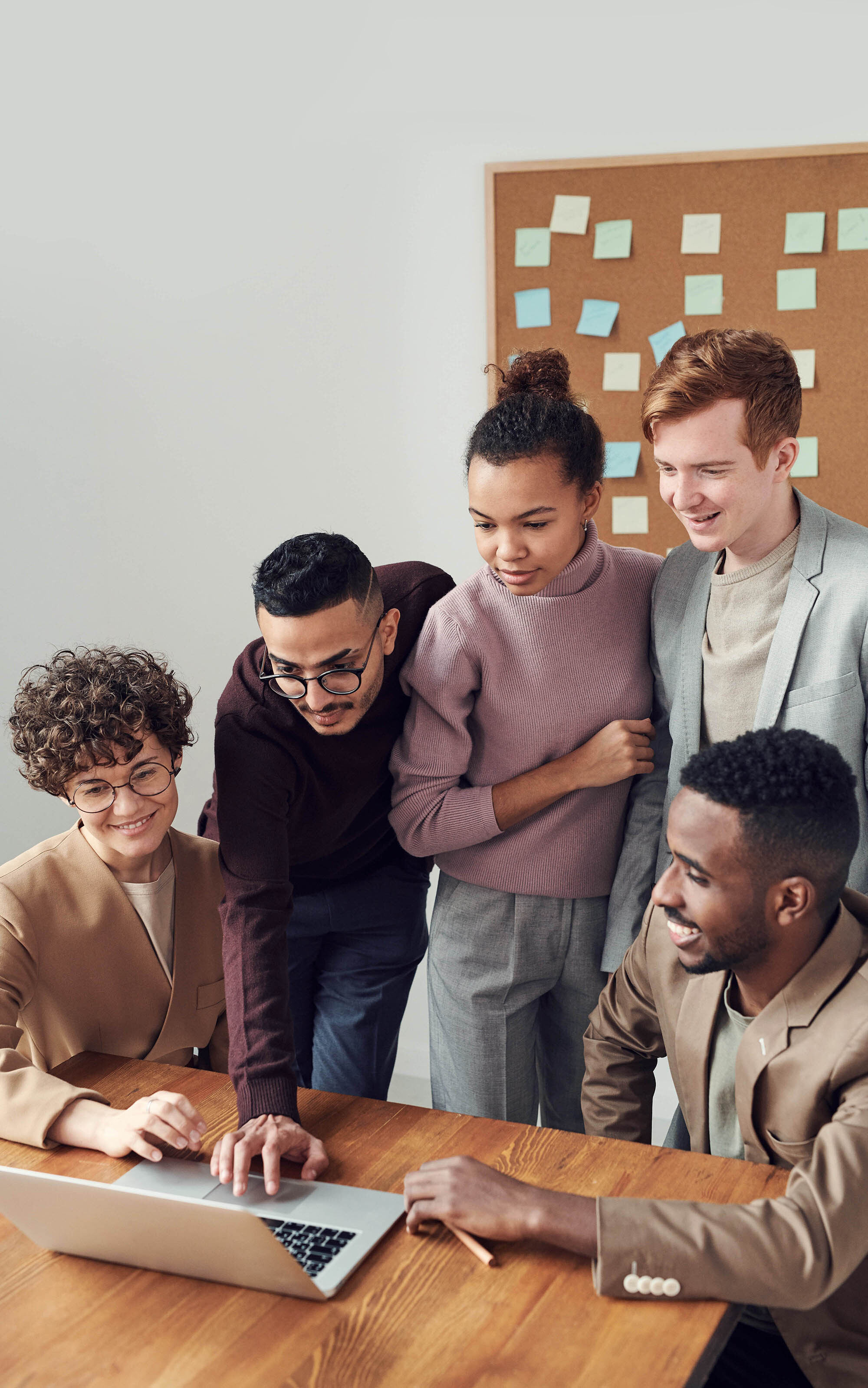five people of various ethnicities in front of a laptop