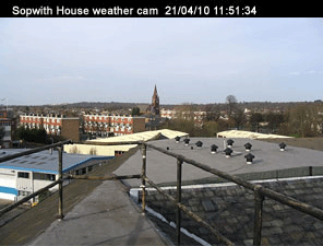 Sopwith house weather cam. Taken on the 21/04/10 at 11:51 and 34 seconds. In the foreground are the safety
rails on the flat part of the roof. Nearby ther are low rise industrial buildings, beyond those are block of flats. In the distance there's a
church steeple.